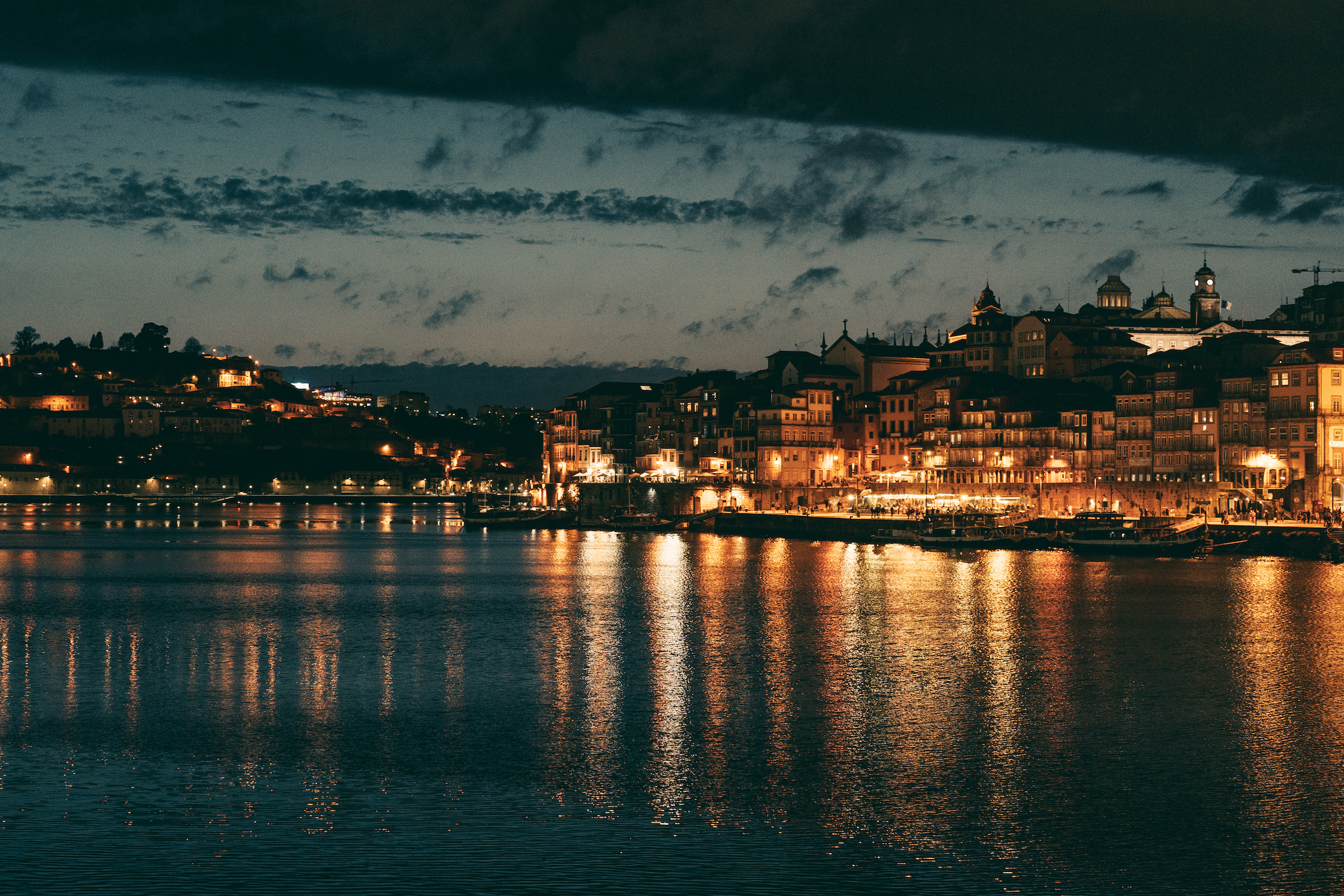 Night view of the city line lit by bright buildings with the Douro river in the foreground