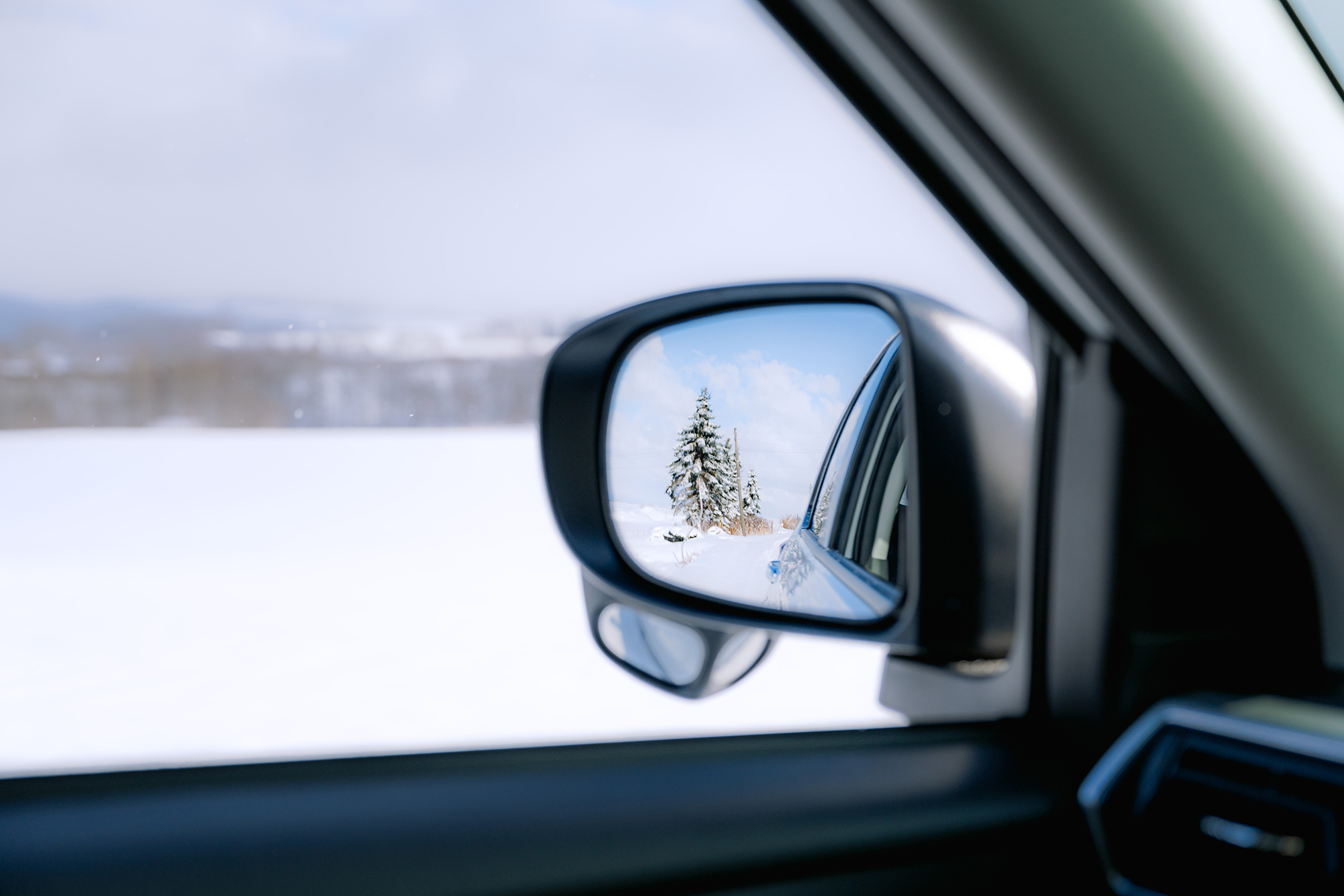 Winter road through the side mirror